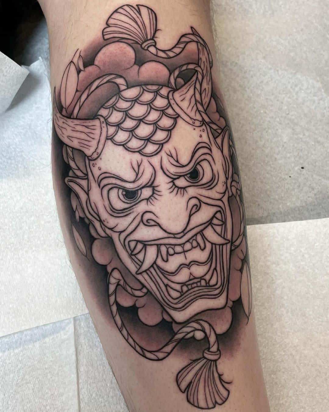 Tatouage détaillé de masque d'oni sur la jambe