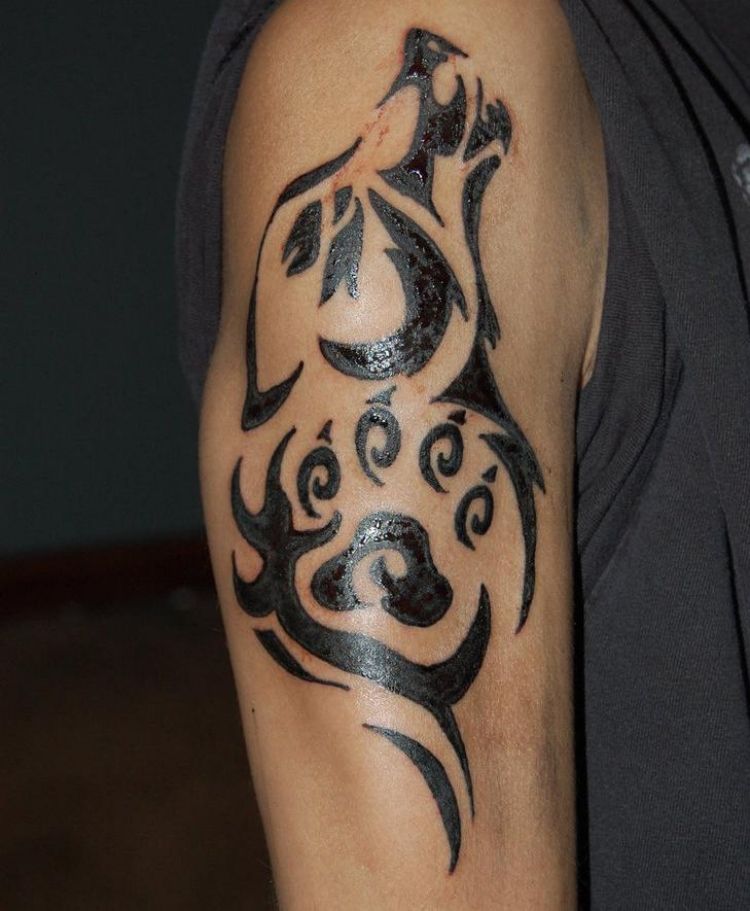 Tatuaj de lup tribal cu labă și umplutură Tatuaj la nivelul brațului superior, mană de lup tribal