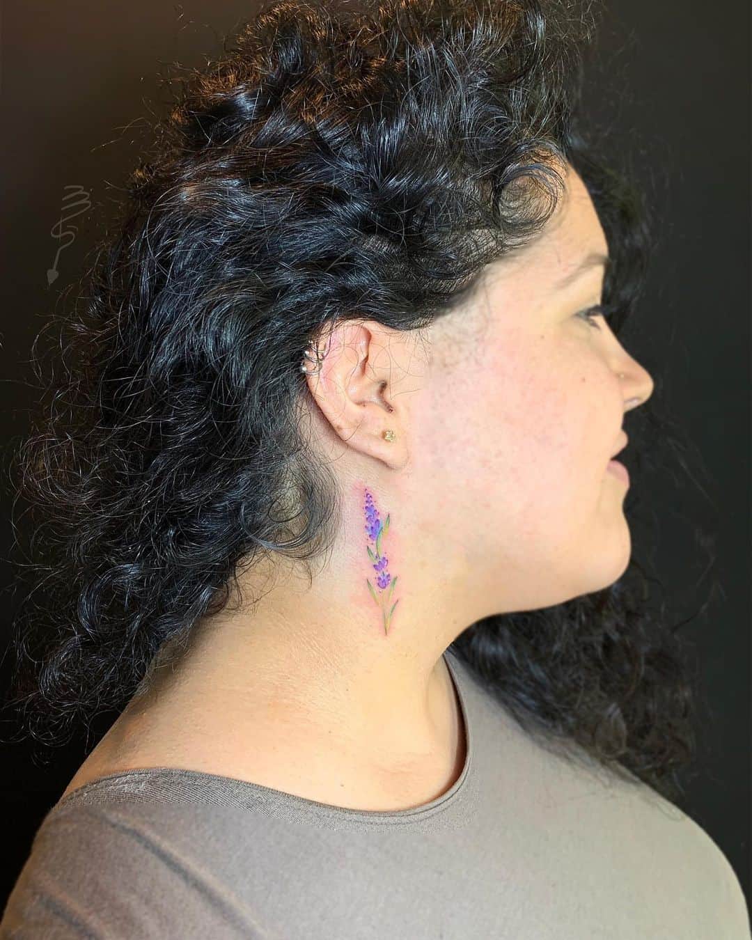Uma tatuagem colorida de lavanda atrás da orelha