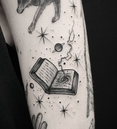 星、惑星、サイクロンのタトゥーで本を開きます。