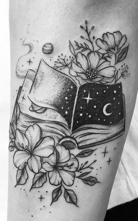 Livre ouvert avec tatouage croissant de lune, étoiles, fleurs et feuilles.