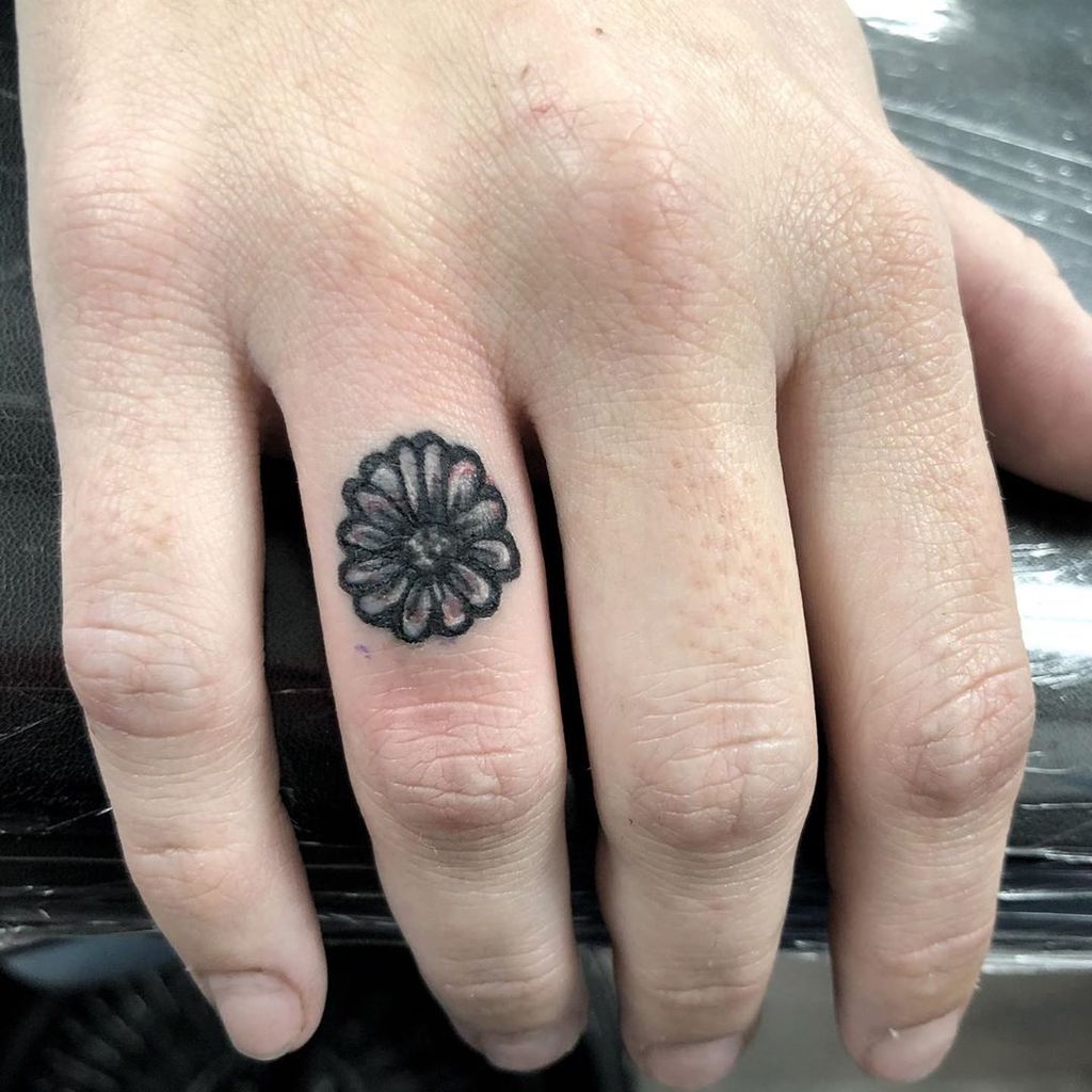 Piccolo tatuaggio margherita sul dito per uomo