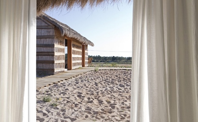Vedere spre casă de vară de la fereastra bungaloulului cu nisip fin Vedere la casă de vară de la fereastra unui bungalou din bambus cu nisip fin
