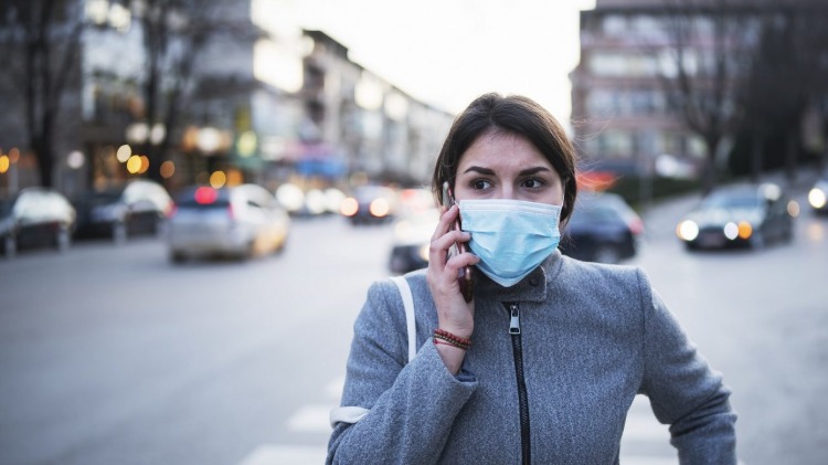 femeie îngrijorată pe stradă cu mască de protecție împotriva virusului covid