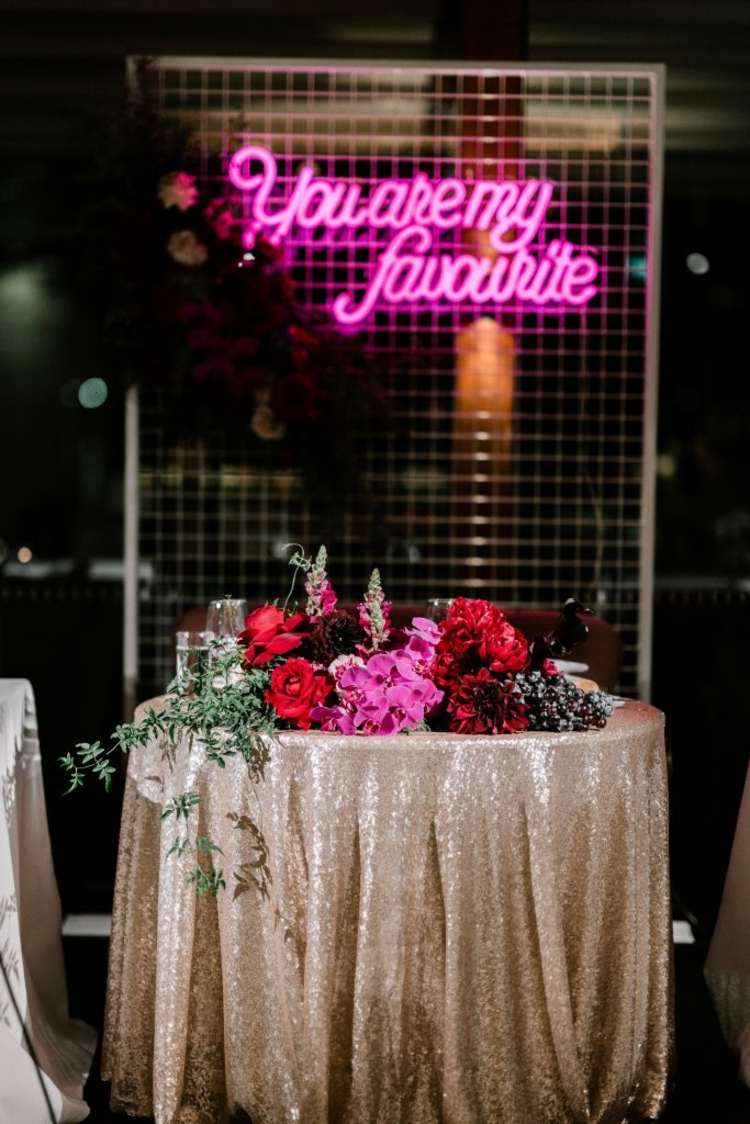 Decor de nuntă plin de farmec în aur cu lumină neon roz în fundal