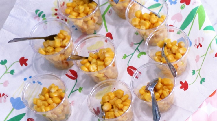 Cesti de porumb cu linguri dispuse pe un servetel colorat pe farfurie rotativa