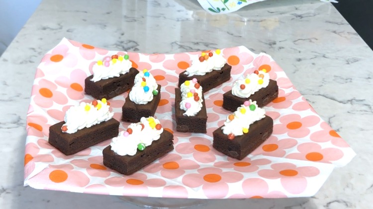 brownies colorate de ciocolată cu o glazură de frișcă și perle de zahăr pe un șervețel