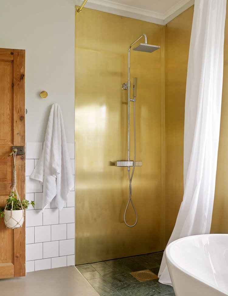 Panourile de perete din alamă din spatele plăcilor de duș din marmură arată verde