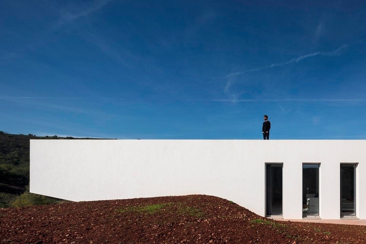 fațadă exterioară albă cu ferestre dispuse una lângă alta, aruncate de soare