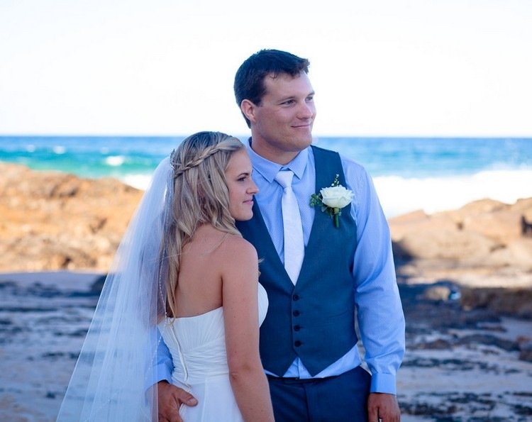 Poartă un costum albastru închis și o cămașă albastră cu cravată albă Nunți-plajă-tricou-albastru-deschis-albastru-întunecat-vestă-trandafir-mire