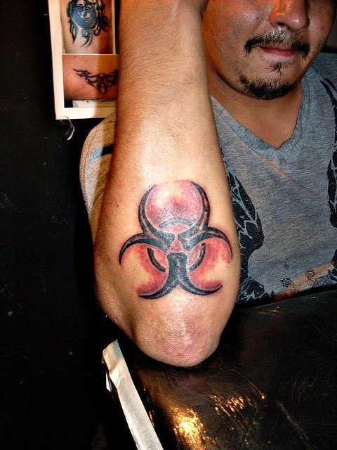 Biologinio pavojaus raudonos juodos spalvos tatuiruotė ant dilbio