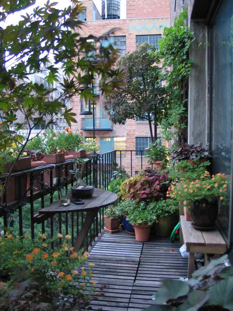 Balcon verde luxuriant ca un fel de grădină în orașul mare masă-balcon-exterior-podele din lemn-plante-pliante-masă-ovală