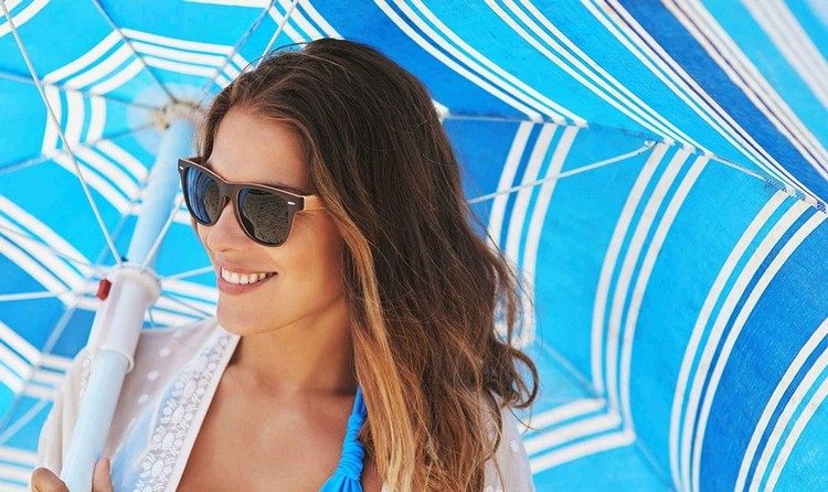 O femeie cu o umbrelă de soare pe plajă vara
