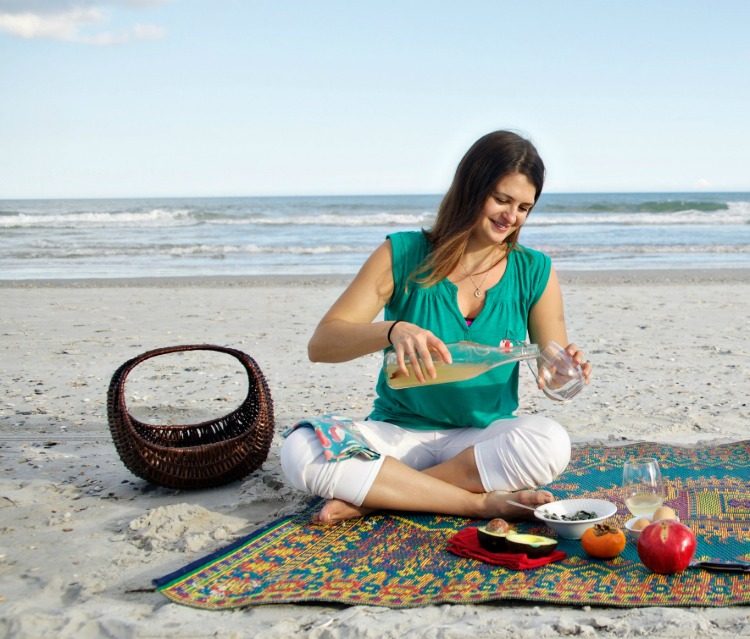 tânără care toarnă băutură probiotică fermentată într-un pahar pe plajă